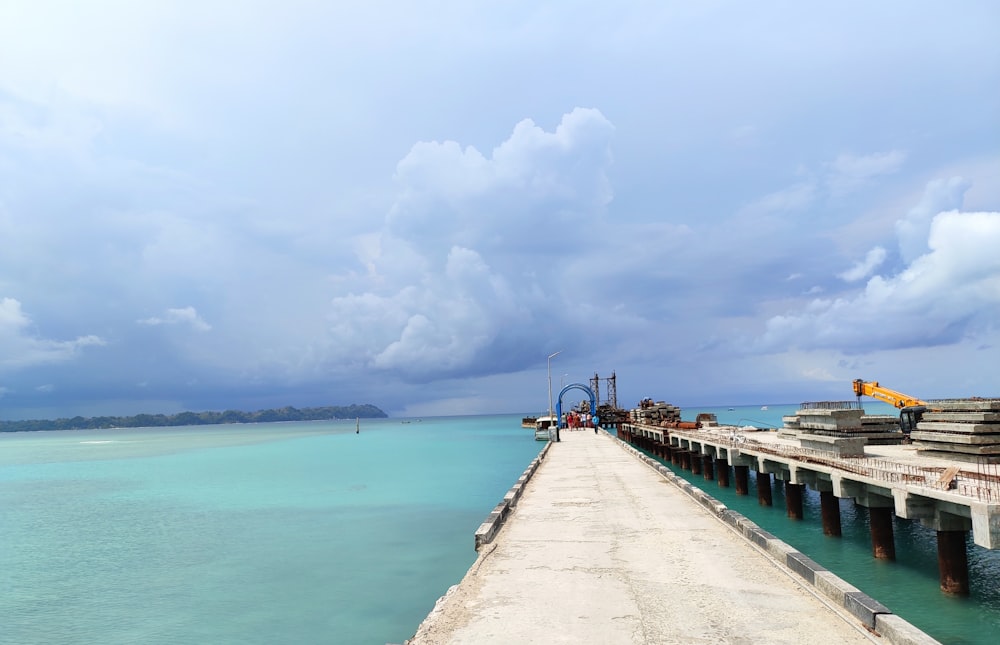 muelle de madera marrón en el mar bajo nubes blancas y cielo azul durante el día