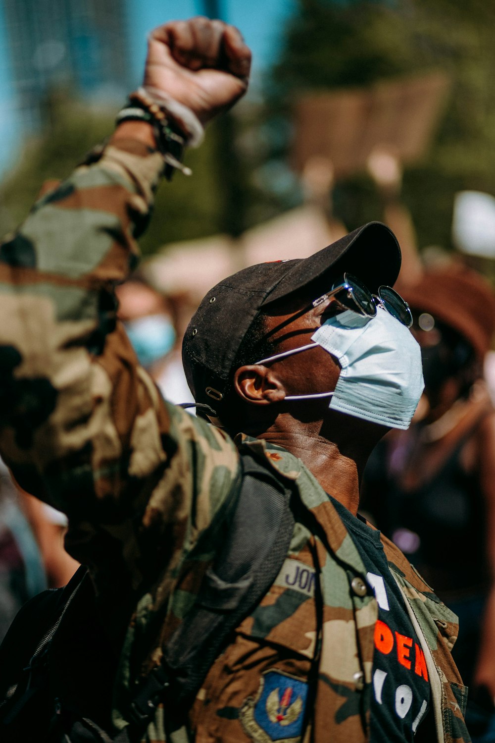 man in green and brown camouflage jacket wearing white sunglasses and white cap