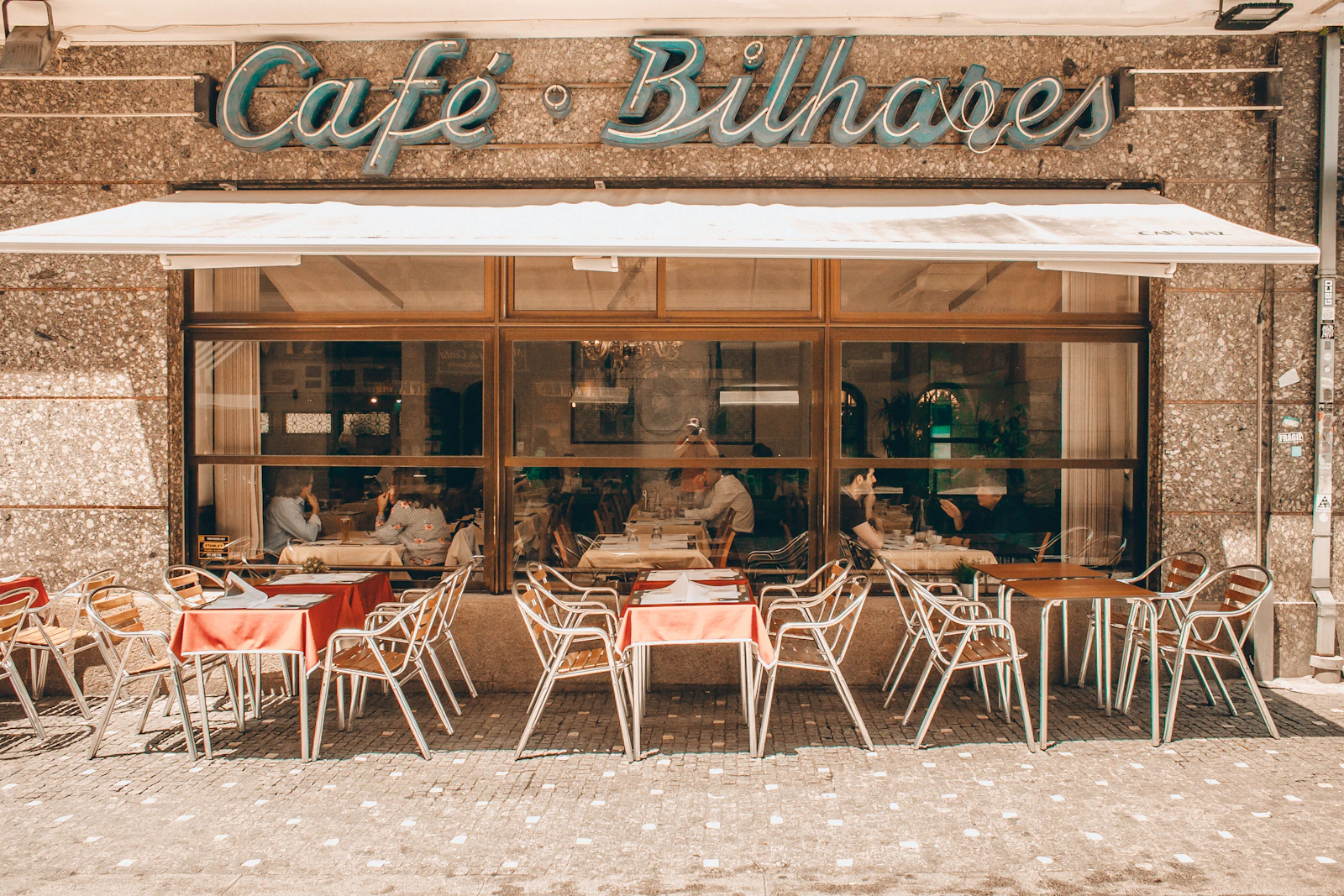 Mesas e cadeiras numa esplanada junto a um café no Porto