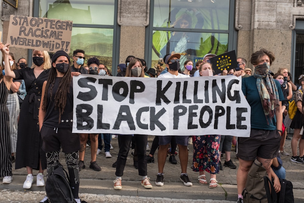 people holding black and white welcome to the beach signage