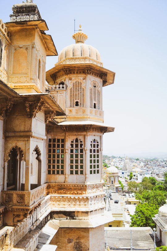 beige concrete building near body of water during daytime in Udaipur India