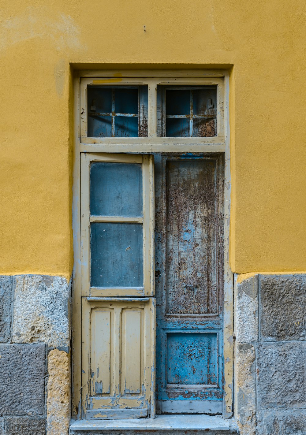 blue wooden window on yellow concrete wall
