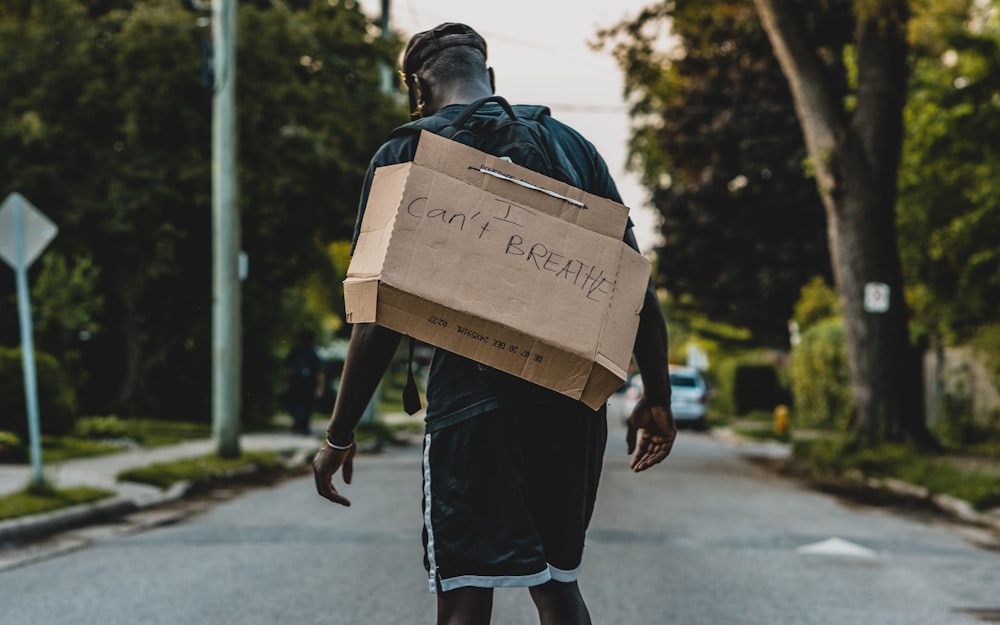 man in black jacket carrying brown cardboard box