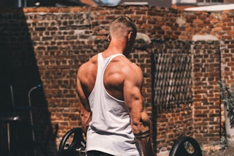 man in white tank top and black and white shorts sitting on black wheel chair