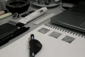 A creative workspace with camera equipment, graphic design tools, and handwritten lyrics.