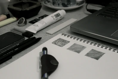 An artist's workspace with sketches, pencils, and a laptop showing design software.