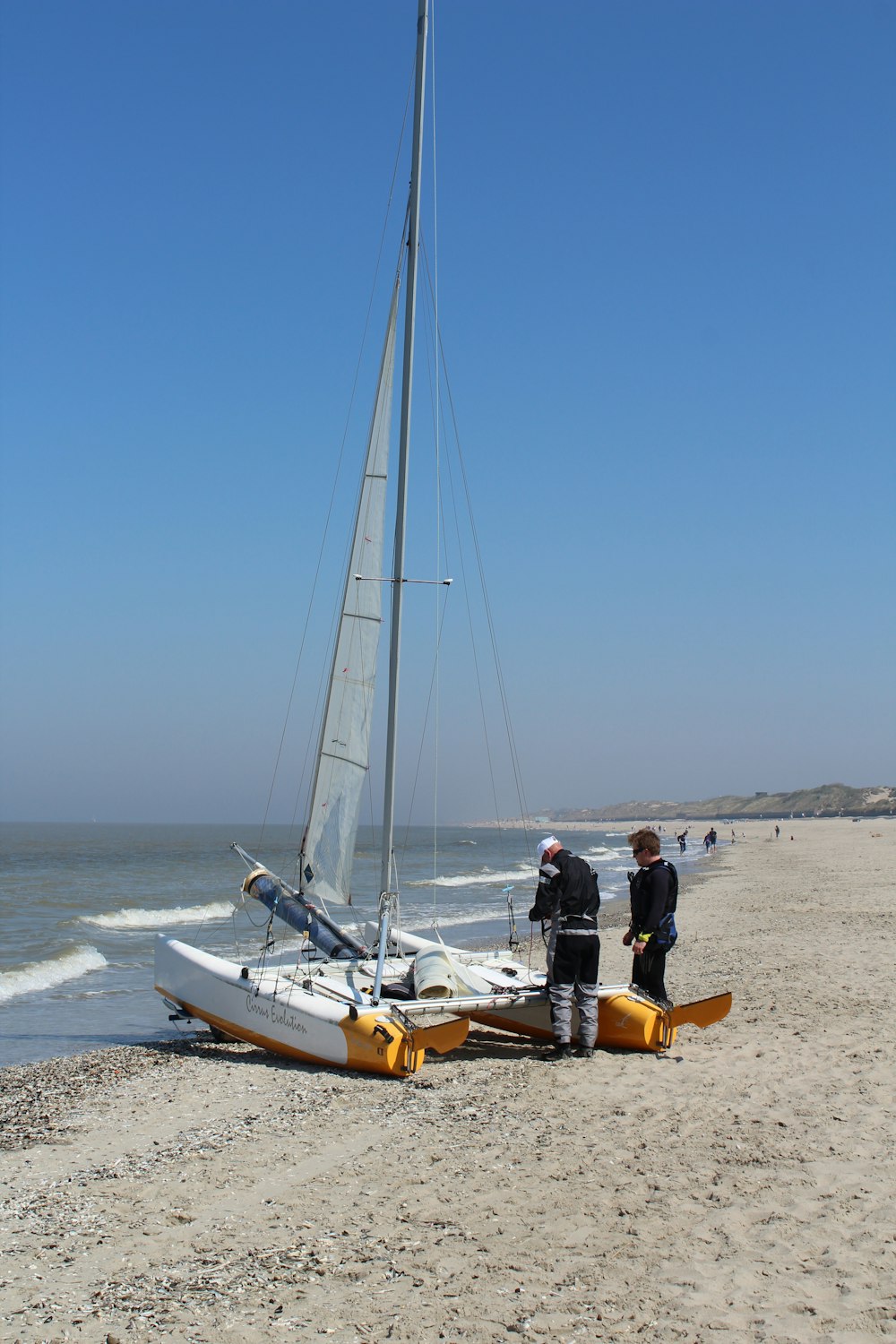 man in black shirt sitting on white and yellow sail boat on sea shore during daytime