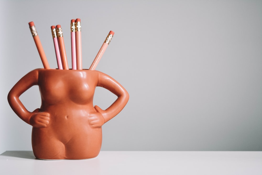 brown ceramic mug with pencils