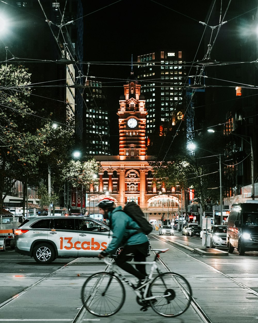 夜間に道路を自転車で走る黒いジャケットを着た男性