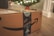 A cardboard box with Amazon branding sits on a wooden floor, with festive blue decorative tape featuring holiday motifs. In the background, a blurred image of a Christmas tree illuminated with lights can be seen, along with a few red and silver ornaments.