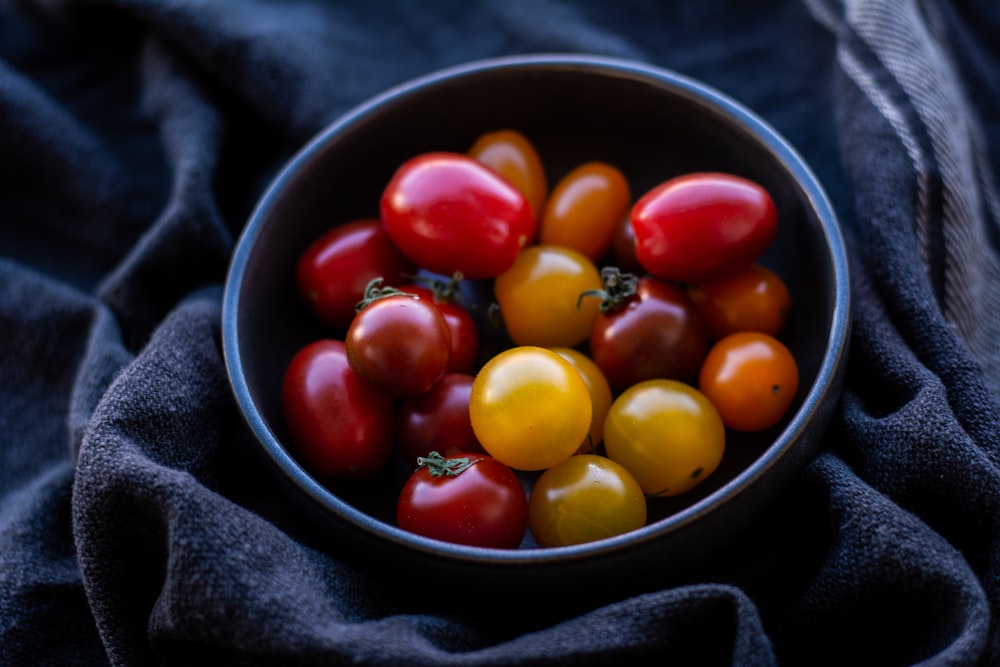 red and yellow round fruits on black ceramic bowl