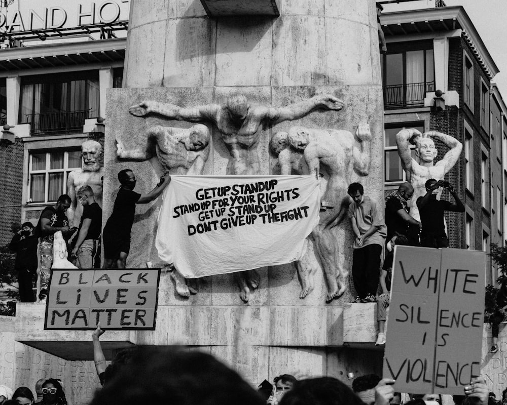 grayscale photo of people standing near lion statue