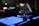 A close-up view of a music production or DJ setup in a dimly lit environment. Illuminated buttons and knobs on a controller are prominently featured, with a laptop displaying audio software in the background. The scene gives a technological and creative vibe.