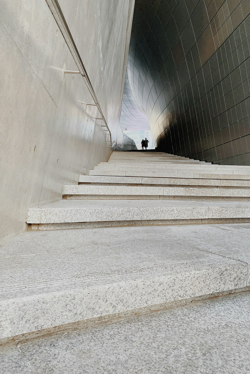 man in black jacket walking on gray concrete stairs