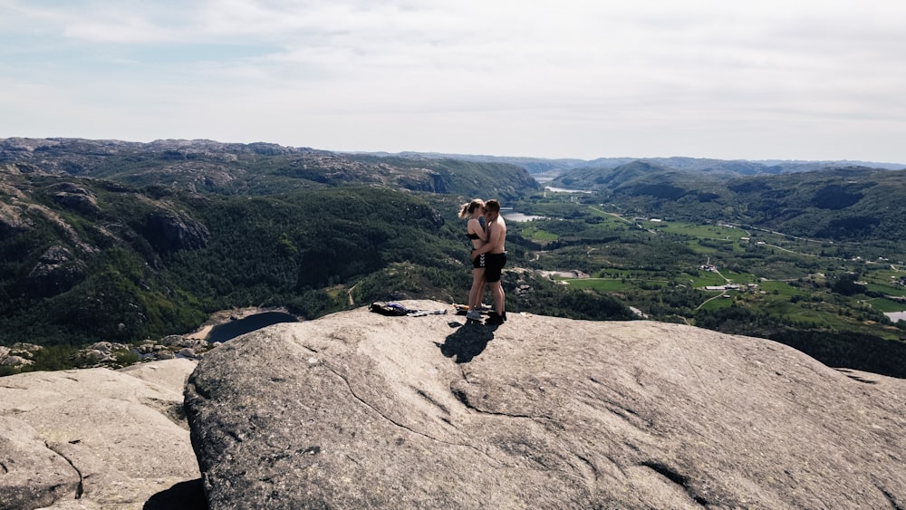 woman in black tank top and black shorts sitting on brown rock formation during daytime