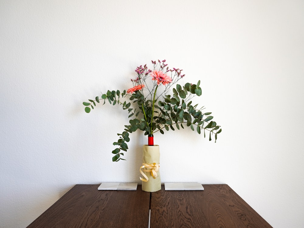 red flowers in white ceramic vase on brown wooden table