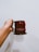 A hand holding a red mug with 'Radio Mirchi' printed on it against a plain background.