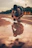 man in black t-shirt and orange pants doing yoga on brown sand during daytime