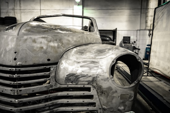 A skilled technician carefully restoring a car's bodywork in a bright, organized workshop.