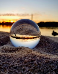 clear glass ball on brown sand during sunset