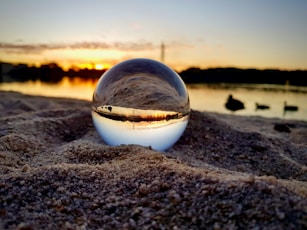 clear glass ball on brown sand during sunset