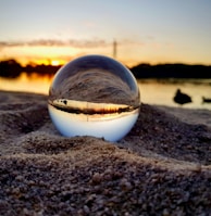 clear glass ball on brown sand during sunset