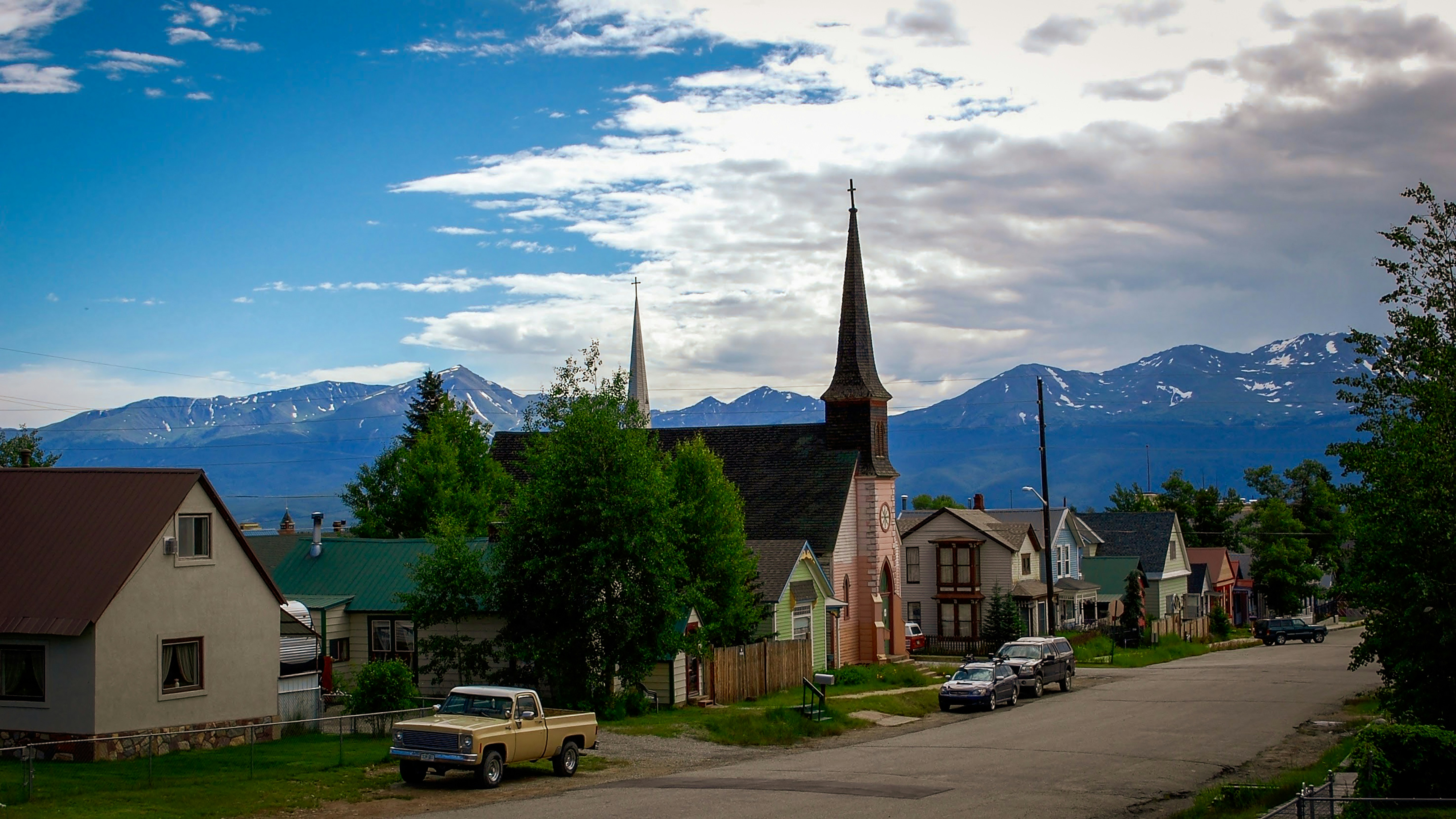 cars parked on parking lot near green trees and brown and white concrete building during daytime, Gorgeous city skyline in the mountains!