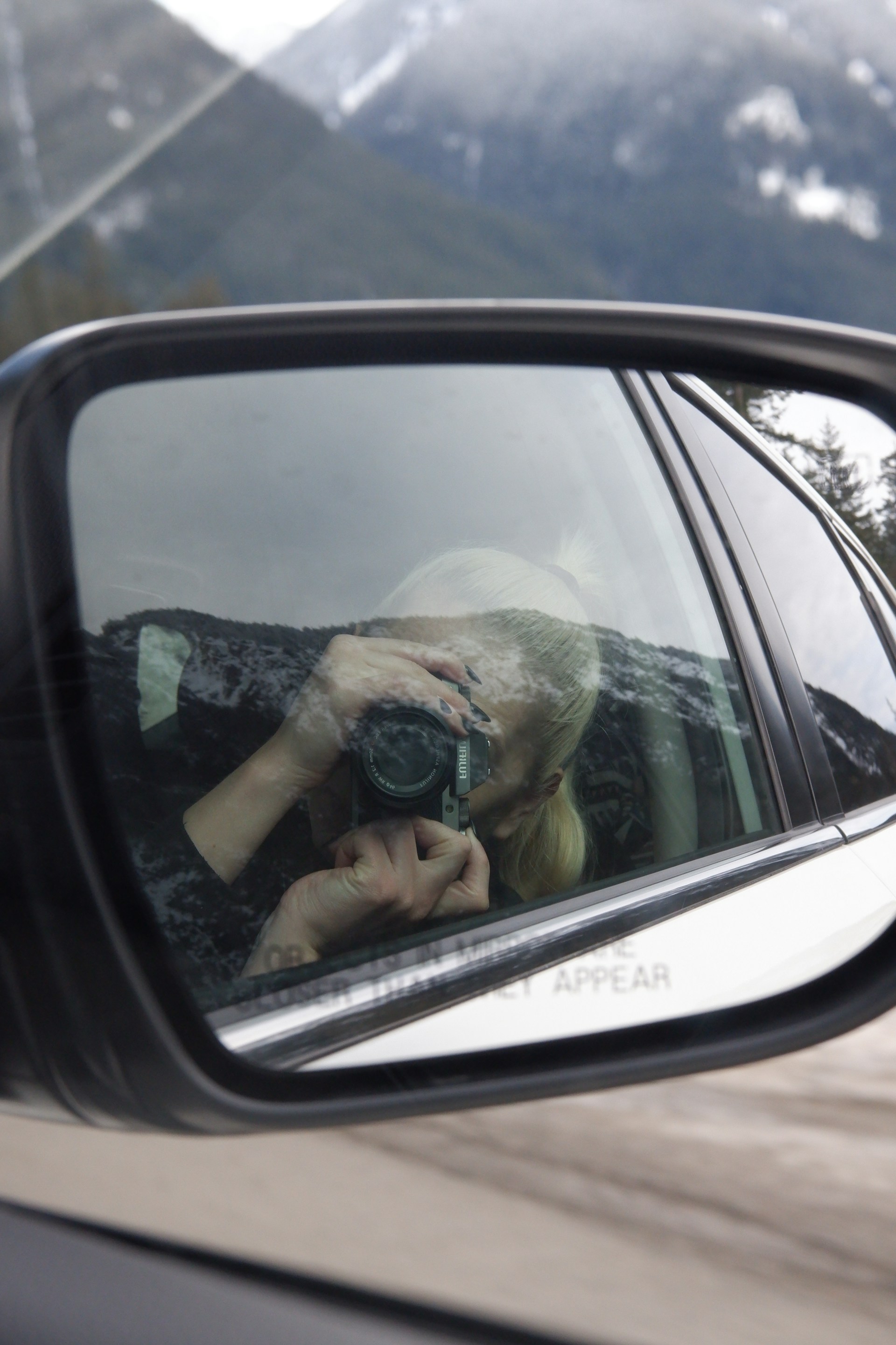 person taking photo of car side mirror
