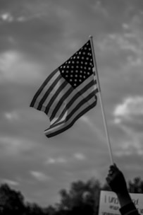 Close-up of hands signing immigration documents with an American flag softly blurred in the background.