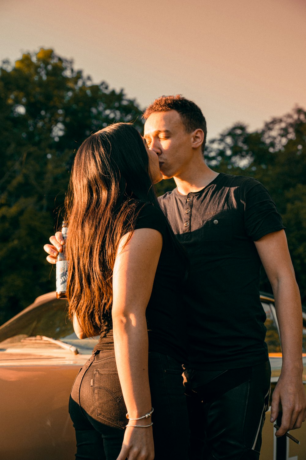 man in black crew neck t-shirt kissing woman in black sleeveless dress during daytime