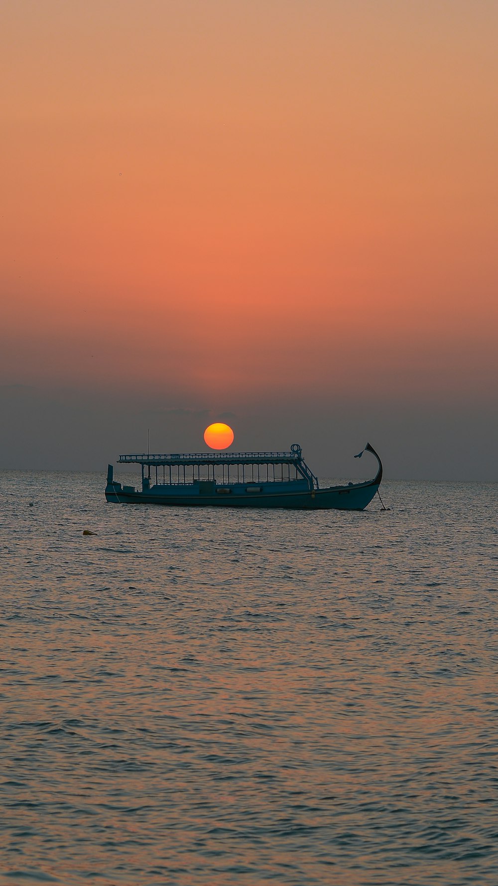 silhouette de bateau sur la mer pendant le coucher du soleil