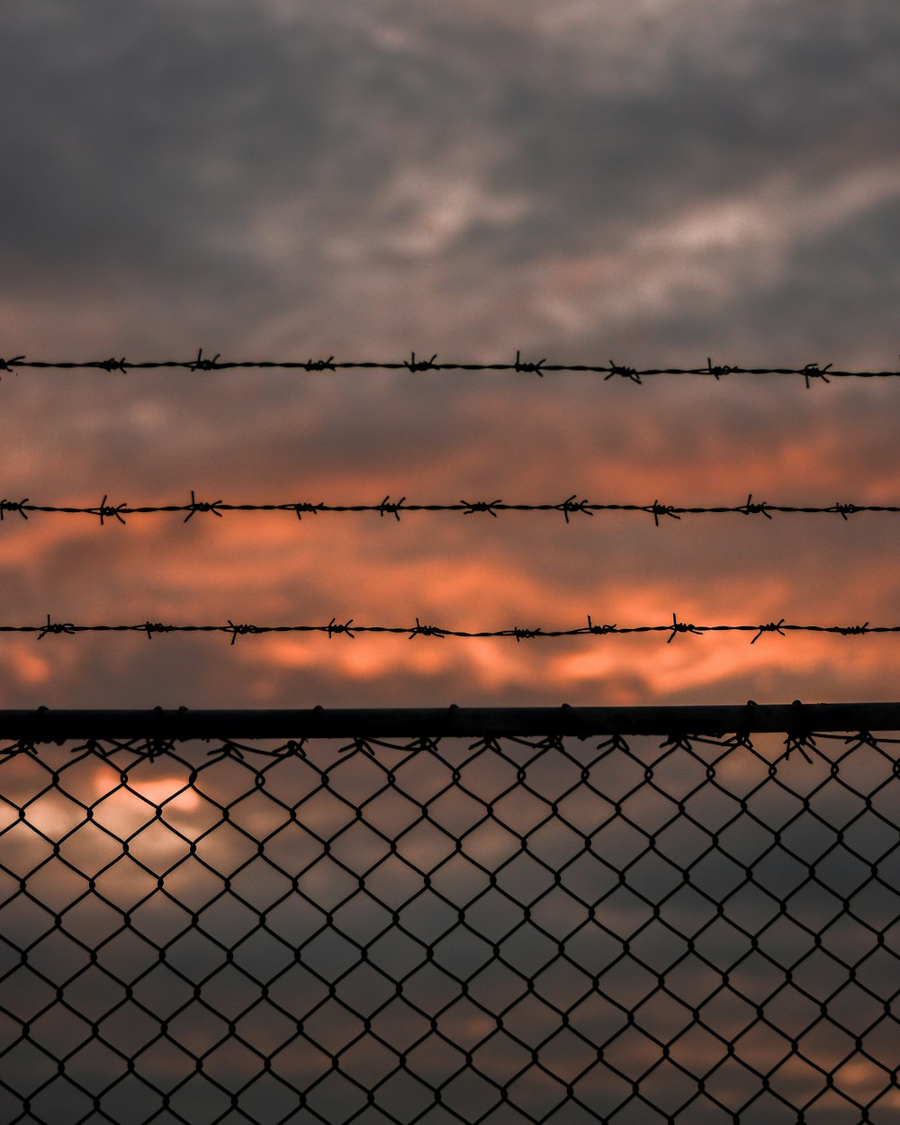 Grauer Metallzaun unter grauen Wolken