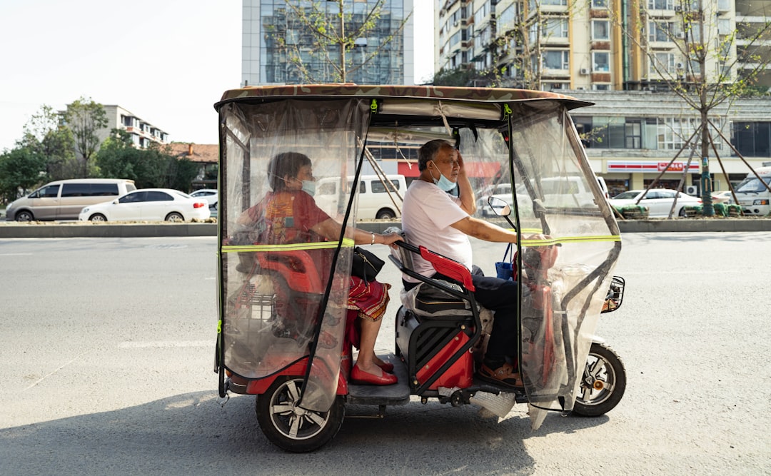 man in white t-shirt riding on black and red auto rickshaw