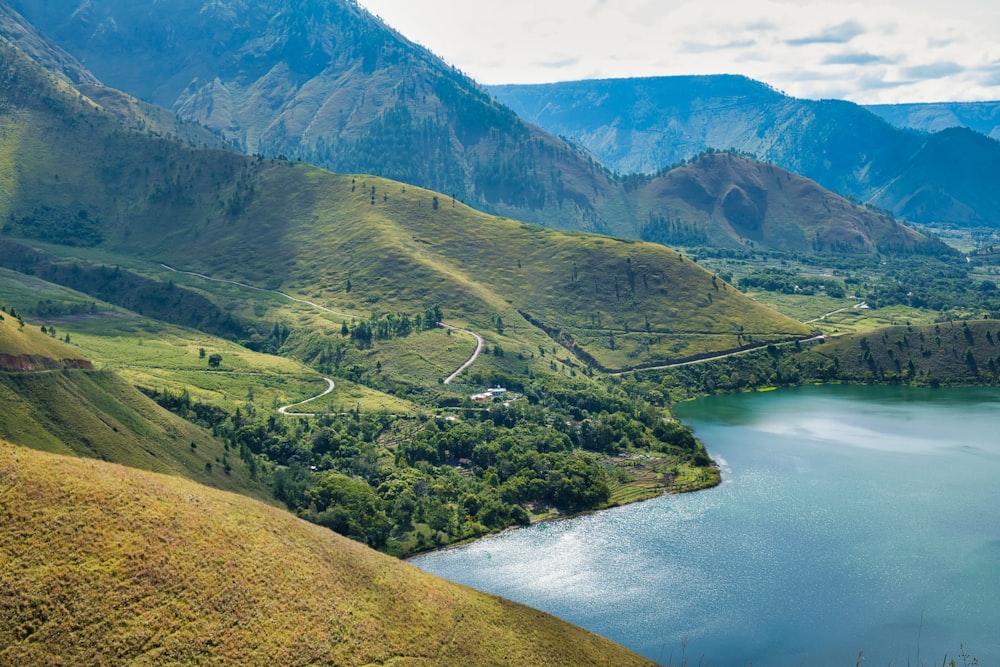 green and brown mountains beside river during daytime