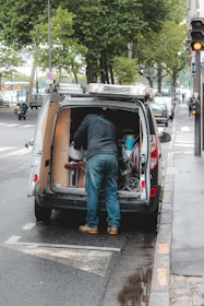 A service van parked outside a home with a technician preparing tools.