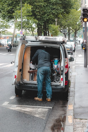 A mobile fitter working on a van's security locks in a parking lot.