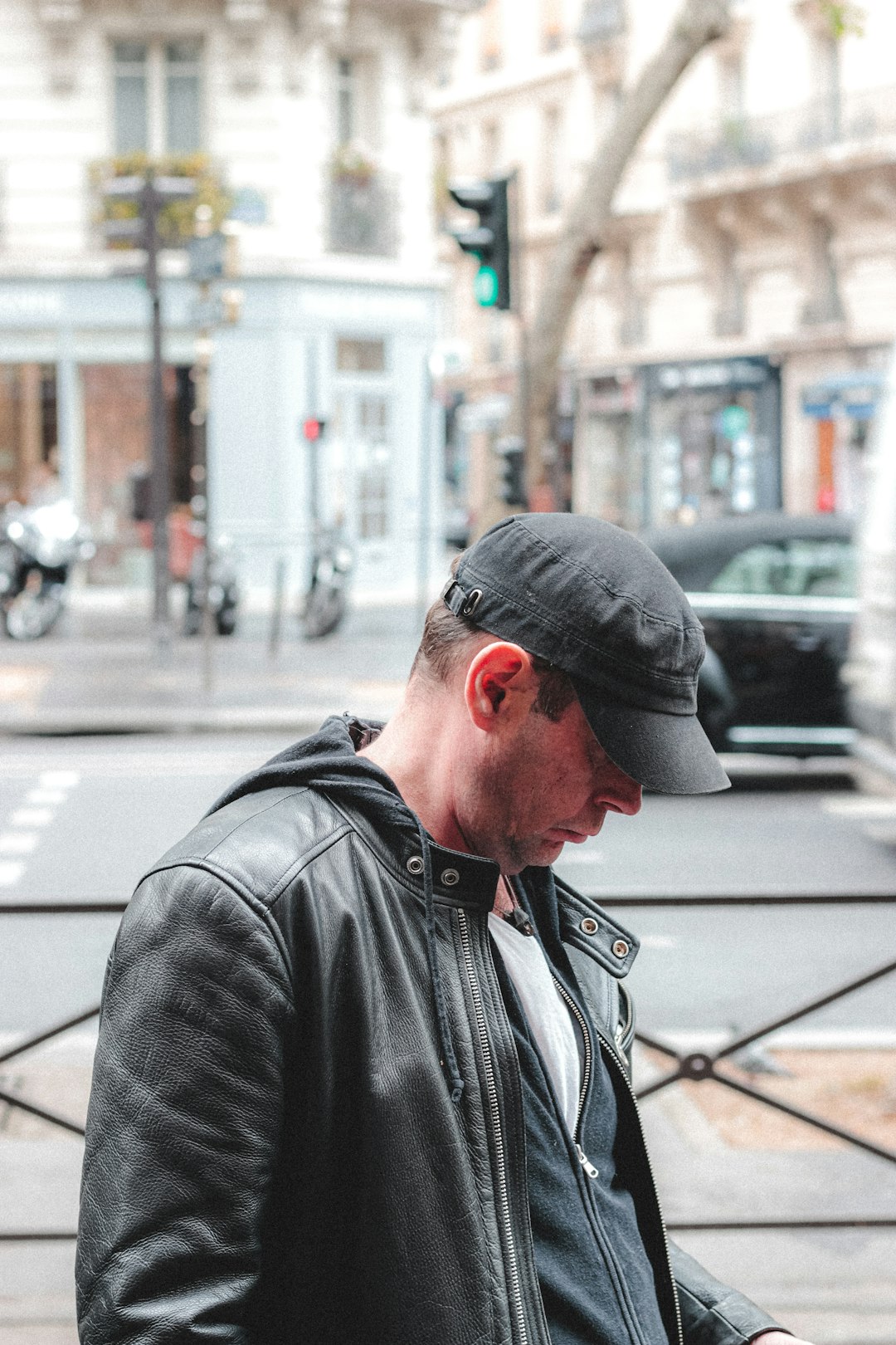 man in black leather jacket and gray knit cap standing on sidewalk during daytime