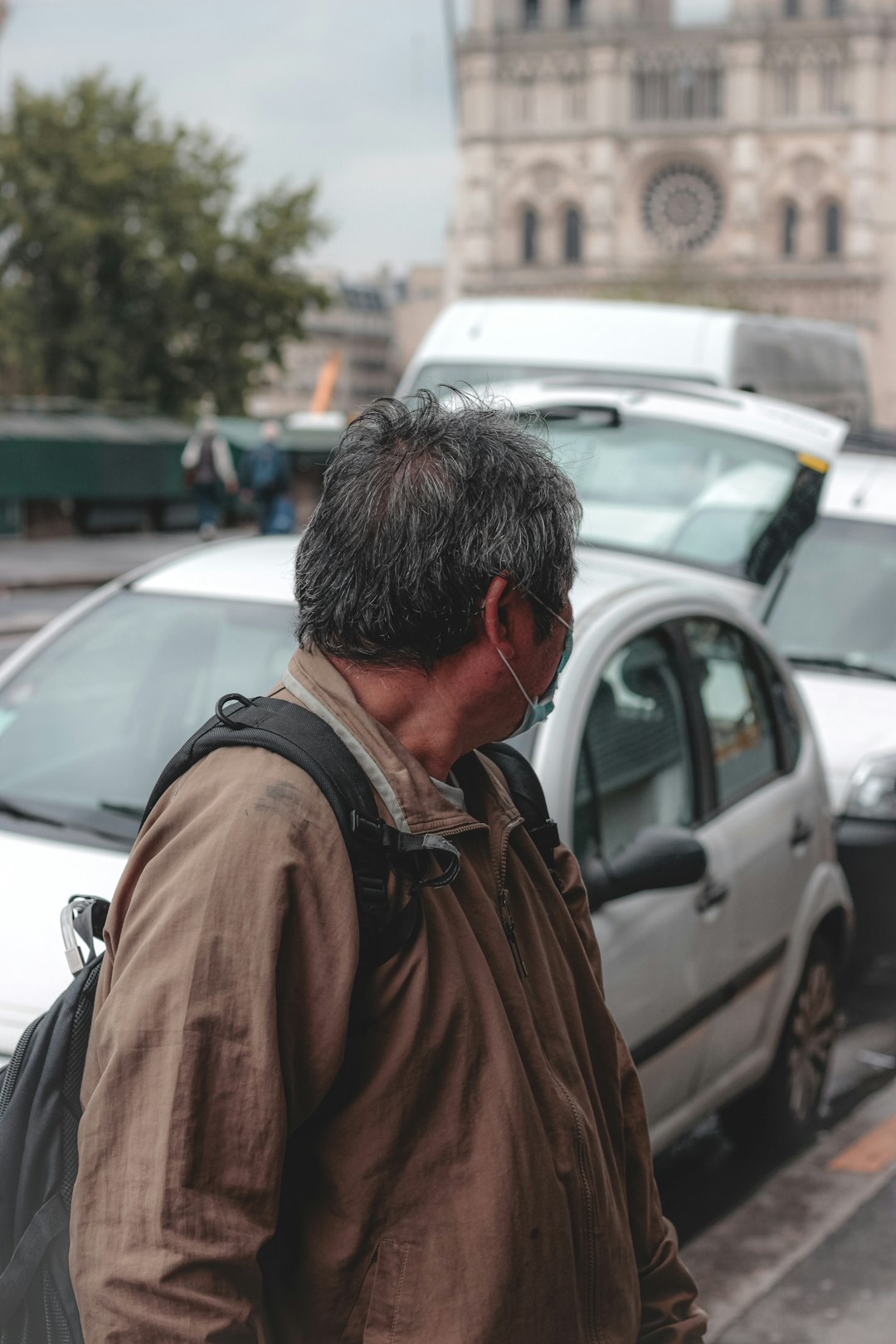 man in brown jacket standing near cars during daytime