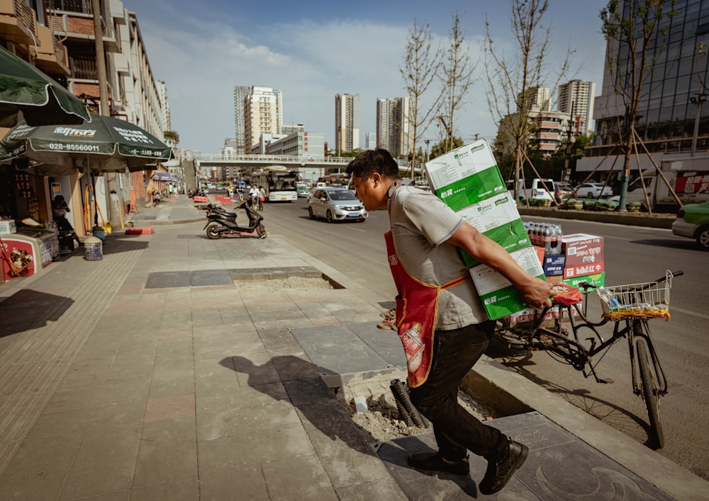 man in red tank top and black pants holding white and green box