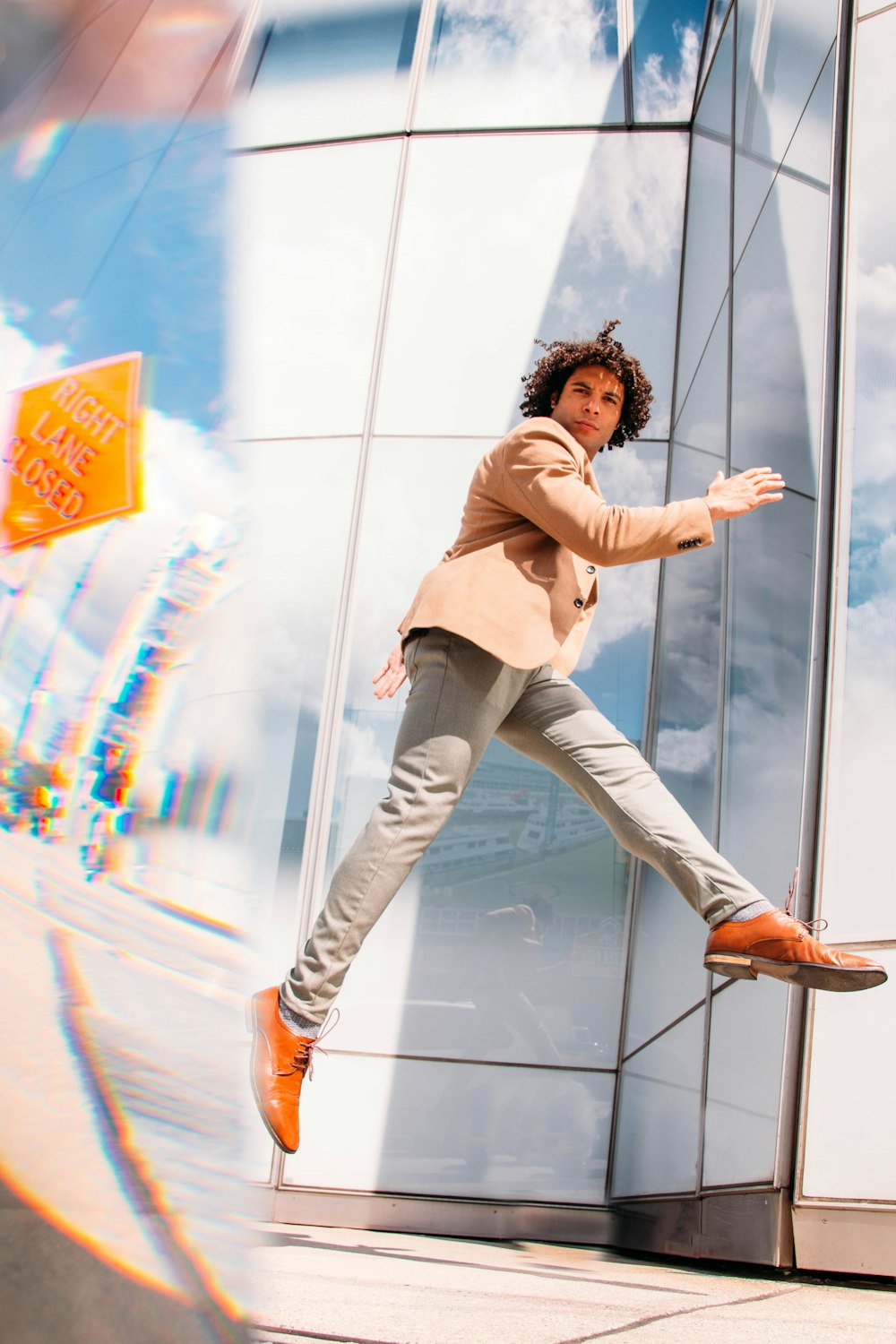 woman in beige long sleeve shirt and gray denim jeans leaning on glass wall