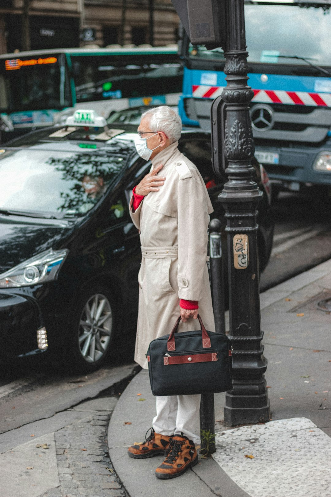 man in white coat standing beside black car during daytime