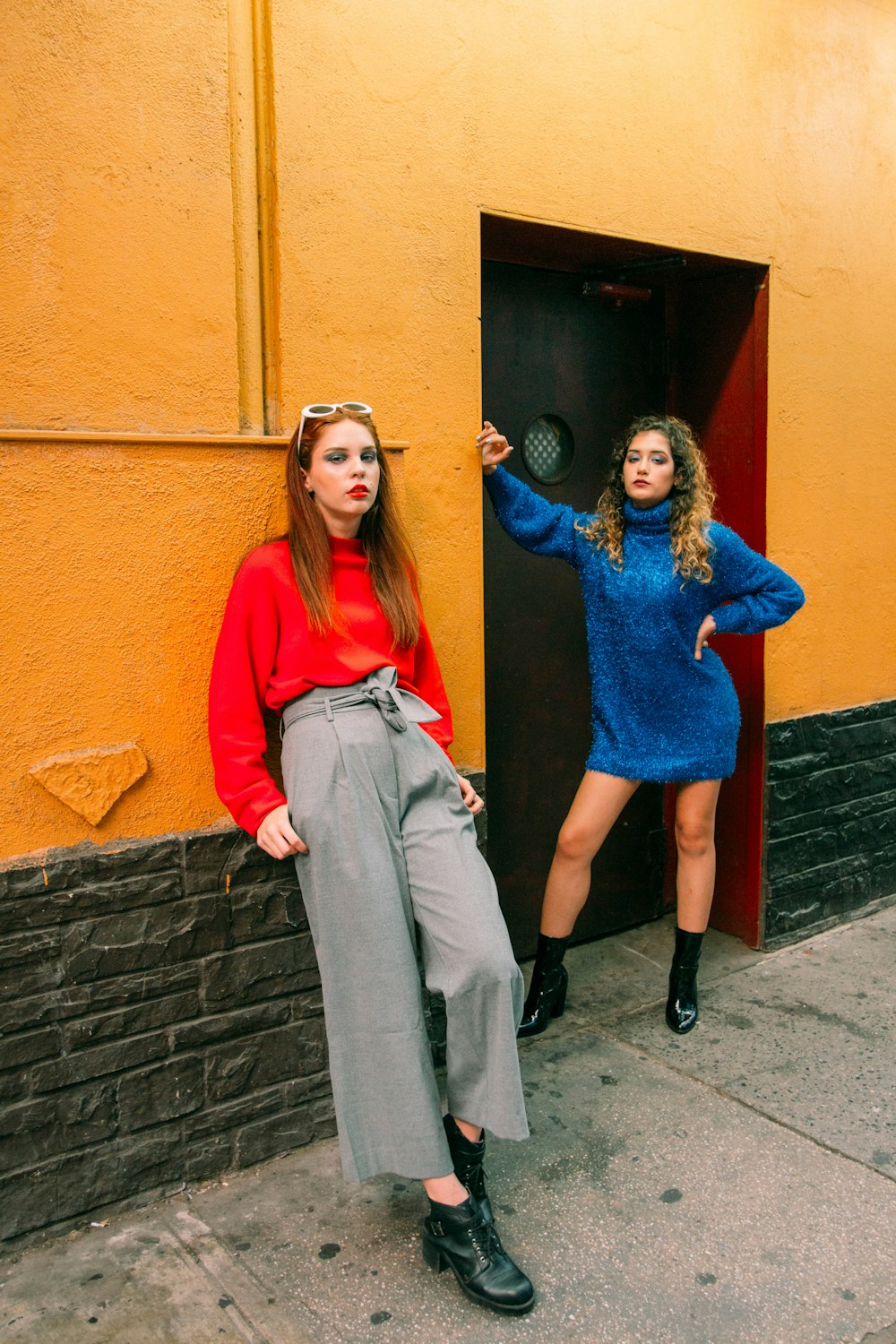 2 women standing beside brown wooden door