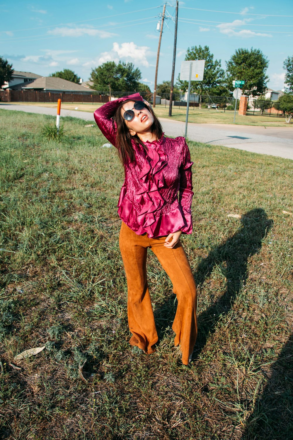 woman in red and black plaid dress shirt and brown pants standing on green grass field