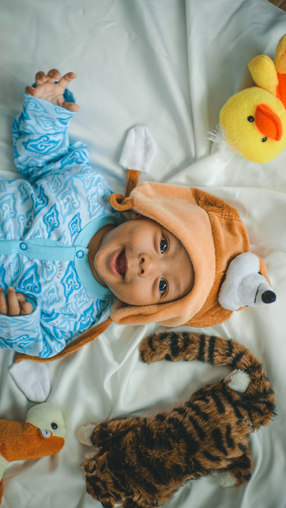 baby in blue and white zip up jacket lying on white textile