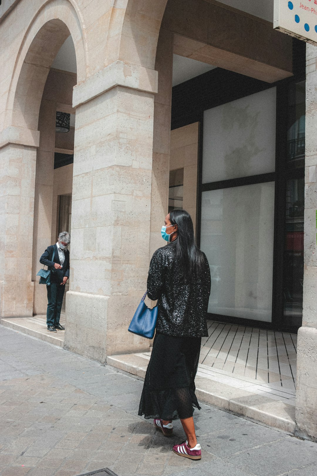 woman in black and white coat standing near brown concrete building during daytime