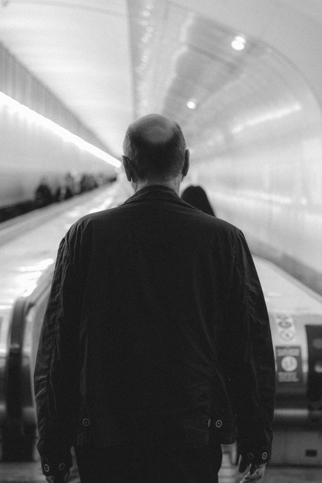man in black suit standing in train station