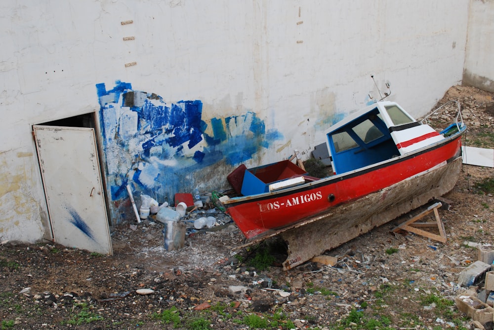 red and white boat beside white wall