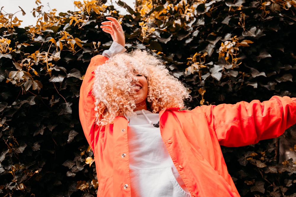 woman in red jacket standing near brown leaves