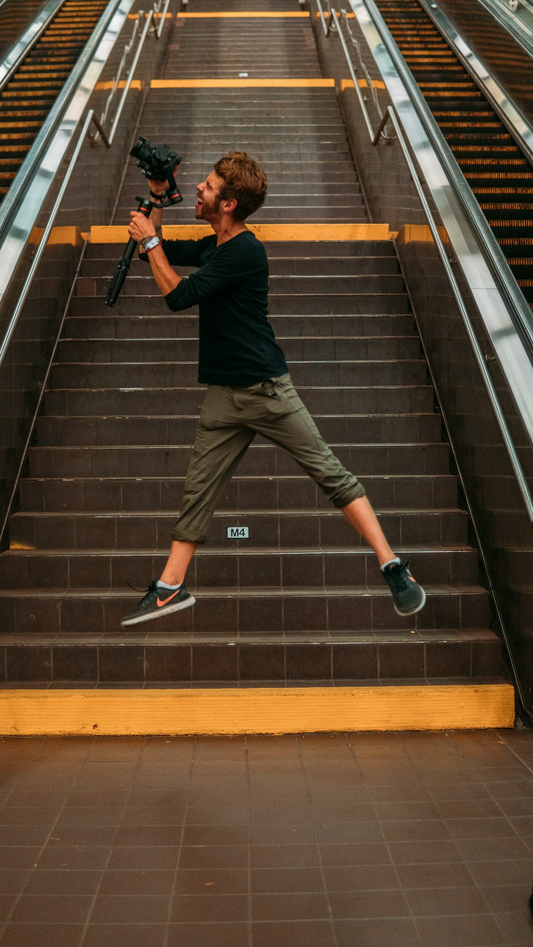 man in black t-shirt and brown pants walking on black and brown staircase