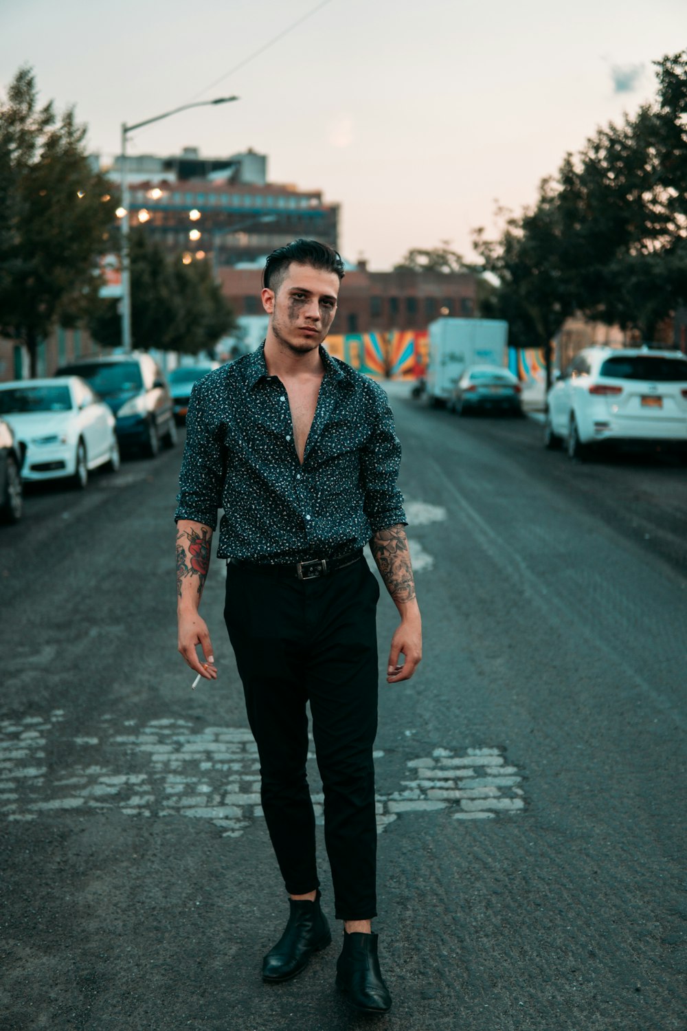 man in red and white dress shirt and black pants standing on road during daytime